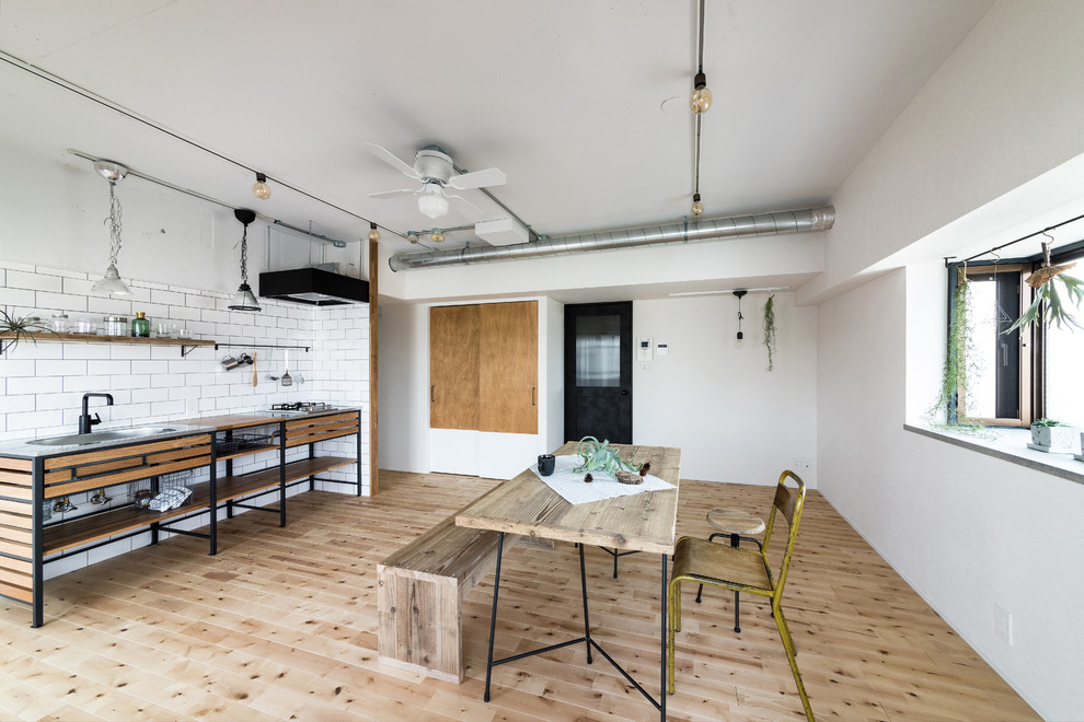 Foto di una sala da pranzo industriale con pareti bianche, parquet chiaro e pavimento beige