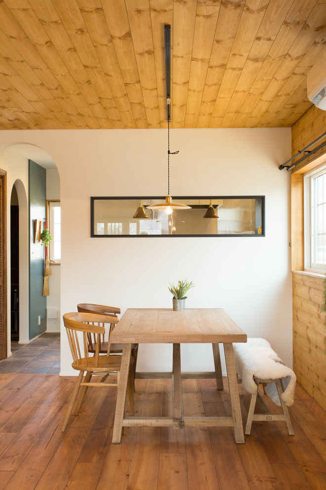 Ispirazione per una sala da pranzo etnica con pareti bianche, pavimento in legno massello medio e pavimento marrone