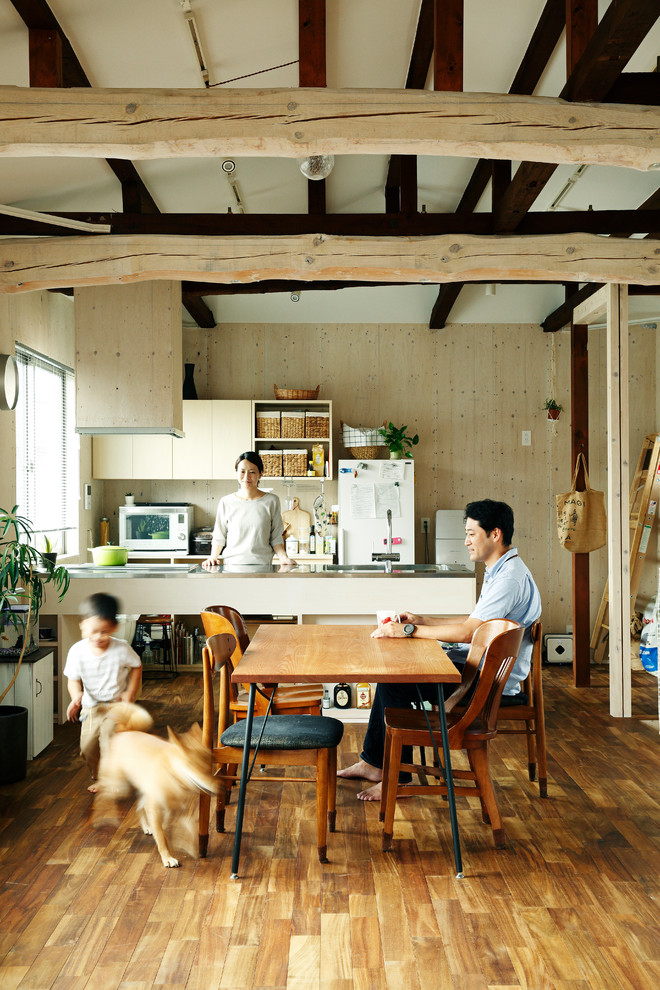 Foto di una sala da pranzo aperta verso il soggiorno industriale con pareti beige, pavimento in legno massello medio e pavimento marrone