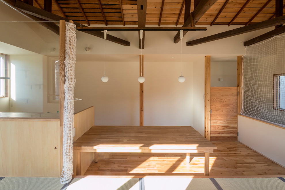 Immagine di una grande sala da pranzo aperta verso il soggiorno etnica con pareti bianche e pavimento in legno massello medio