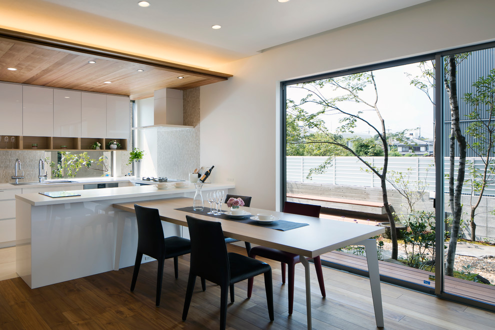 Cette photo montre une salle à manger moderne avec un mur blanc, un sol en bois brun et un sol marron.