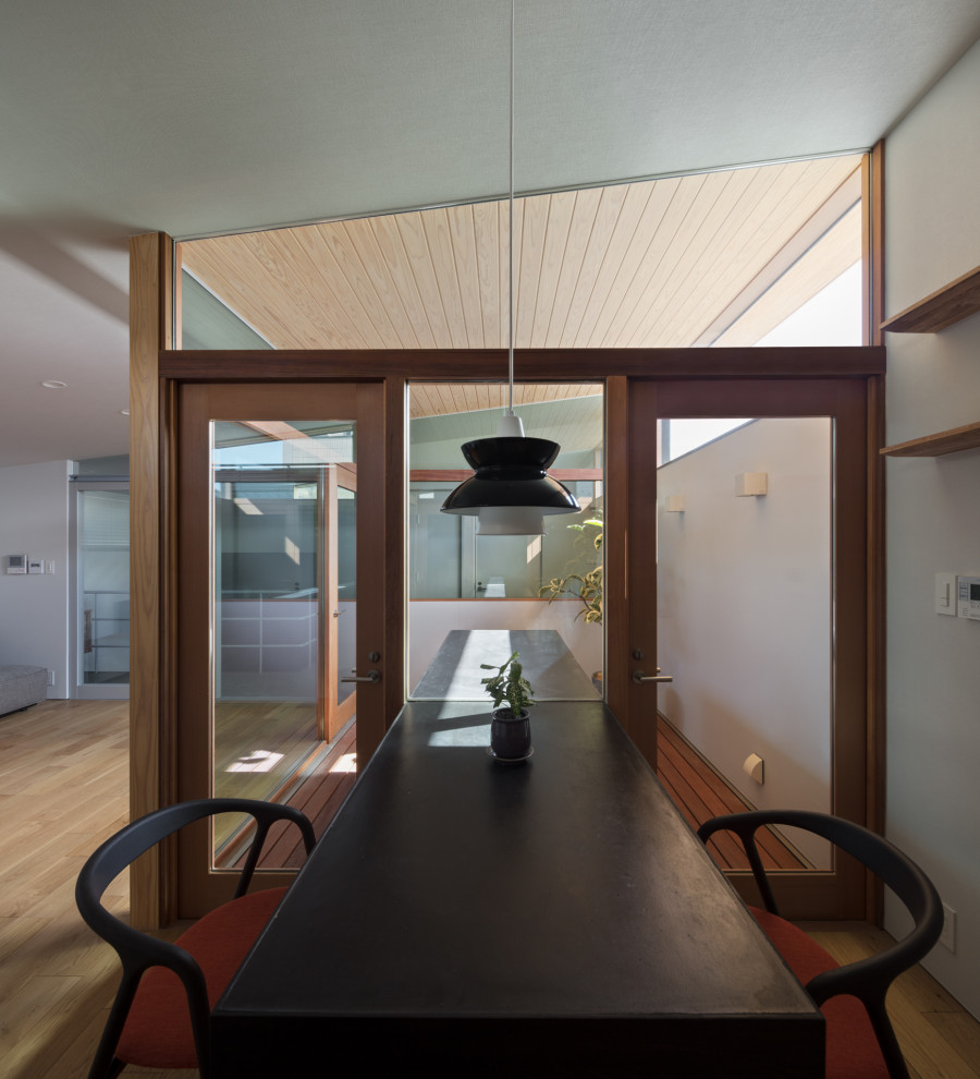 Esempio di una piccola sala da pranzo aperta verso la cucina moderna con pareti bianche e pavimento in compensato