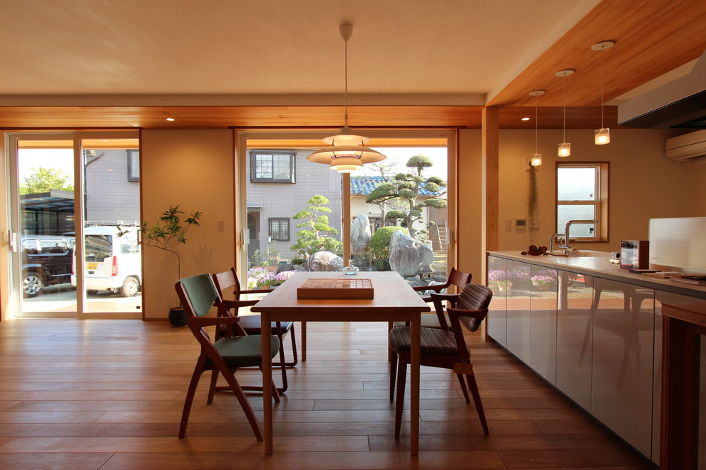Inspiration pour une salle à manger ouverte sur le salon minimaliste avec un mur blanc, un sol en bois brun et un sol marron.