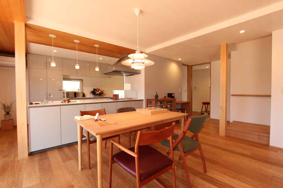 Aménagement d'une salle à manger ouverte sur le salon moderne avec un mur blanc, un sol en bois brun et un sol marron.