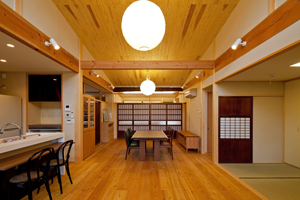 Imagen de comedor asiático abierto con paredes blancas, suelo de madera en tonos medios y suelo marrón