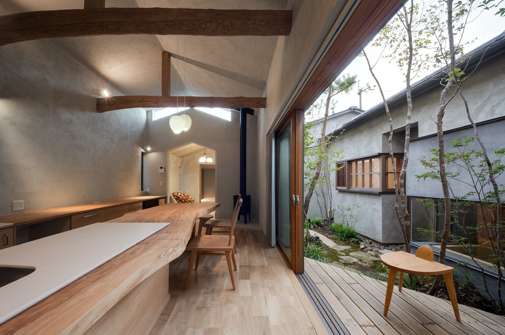 Asiatische Wohnküche mit grauer Wandfarbe, hellem Holzboden, Kaminofen, Kaminumrandung aus Beton und beigem Boden in Osaka