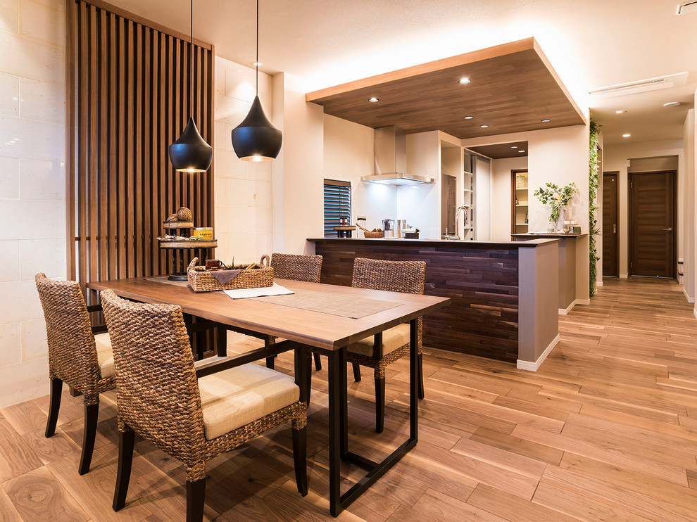 Cette photo montre une salle à manger ouverte sur la cuisine asiatique avec un mur blanc, un sol marron et un sol en contreplaqué.