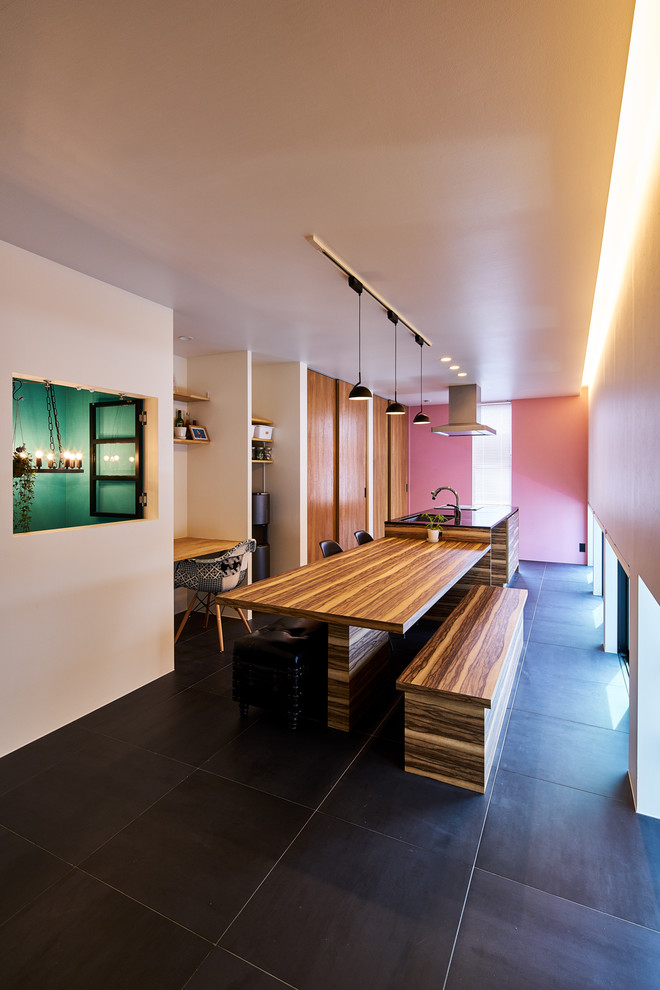 Cette image montre une salle à manger minimaliste avec un mur multicolore et un sol noir.
