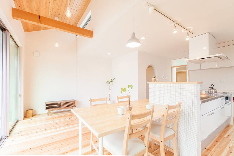 Imagen de comedor moderno pequeño abierto con paredes blancas, suelo de madera clara y suelo beige