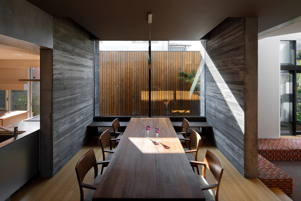 Ejemplo de comedor minimalista abierto con paredes grises, suelo de madera clara y suelo marrón
