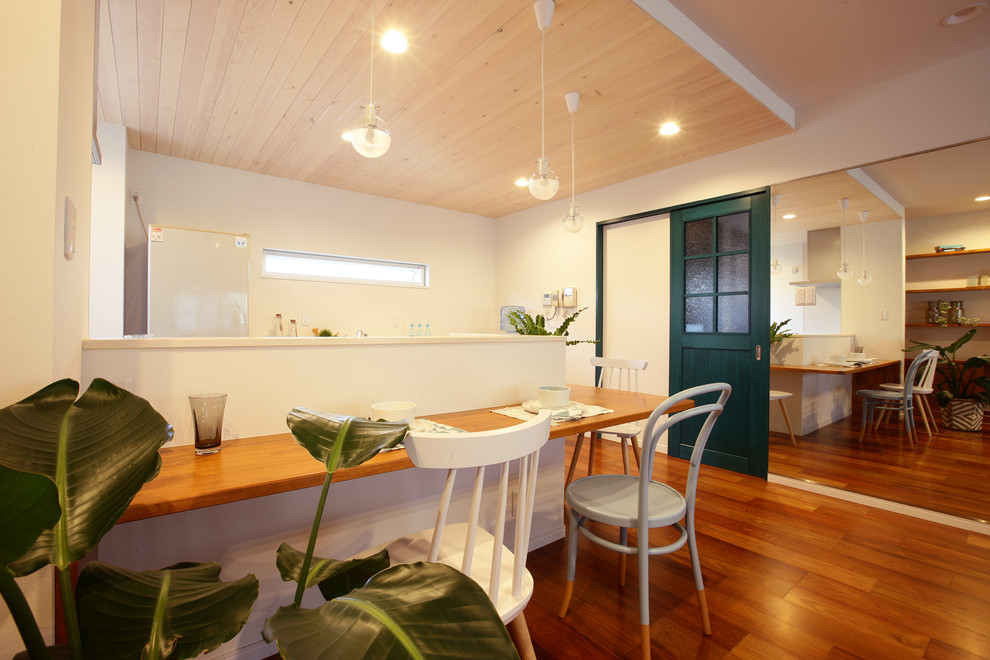 Foto di una sala da pranzo tropicale con pareti bianche, pavimento in legno massello medio e pavimento marrone