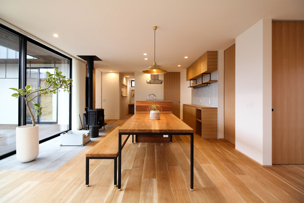 Immagine di una sala da pranzo etnica con pareti bianche, pavimento in legno massello medio e pavimento marrone