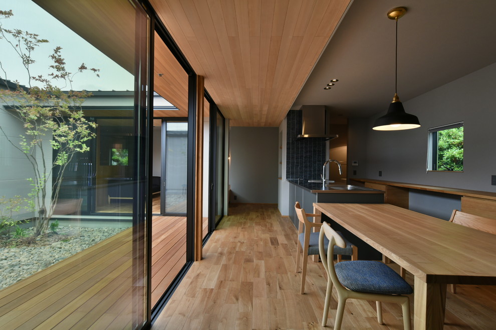 Exemple d'une salle à manger tendance avec un mur gris, un sol en bois brun et un sol marron.