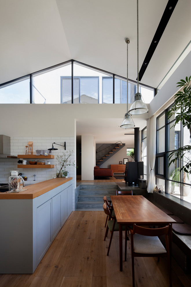 Moderne Wohnküche mit braunem Holzboden und Kaminofen in Sonstige