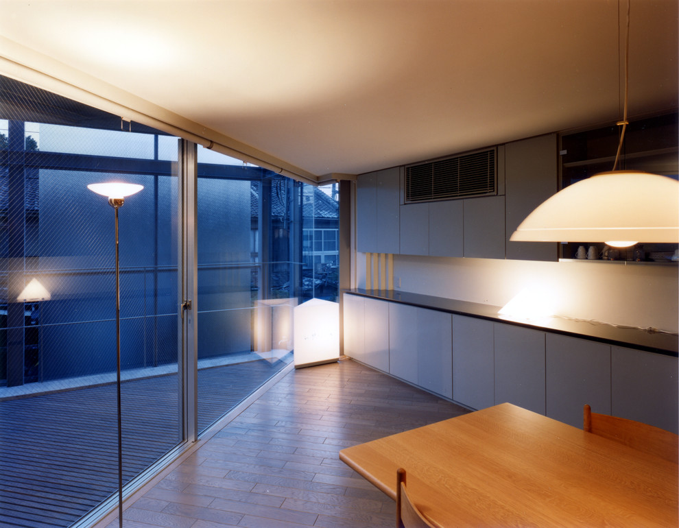 Cette photo montre une salle à manger ouverte sur la cuisine de taille moyenne avec un mur gris, parquet peint, aucune cheminée et un sol gris.