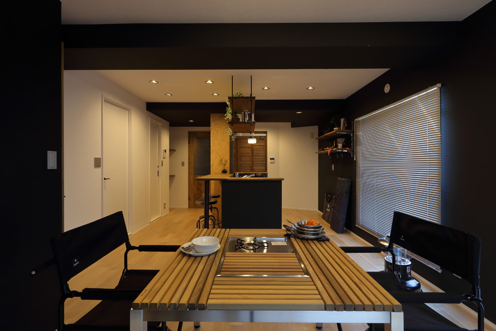 Diseño de comedor moderno de tamaño medio sin chimenea con paredes negras y suelo de madera clara