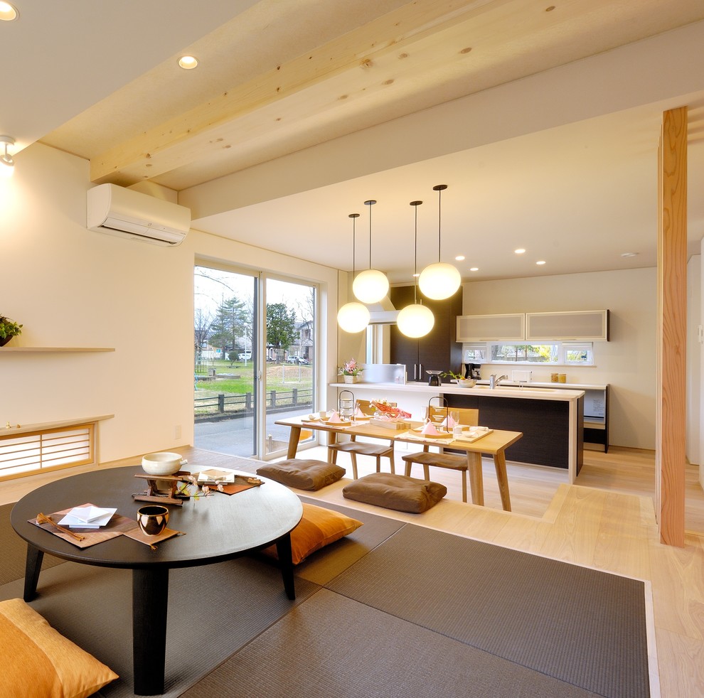 Modelo de comedor de estilo zen abierto con paredes blancas, suelo de madera clara y suelo beige