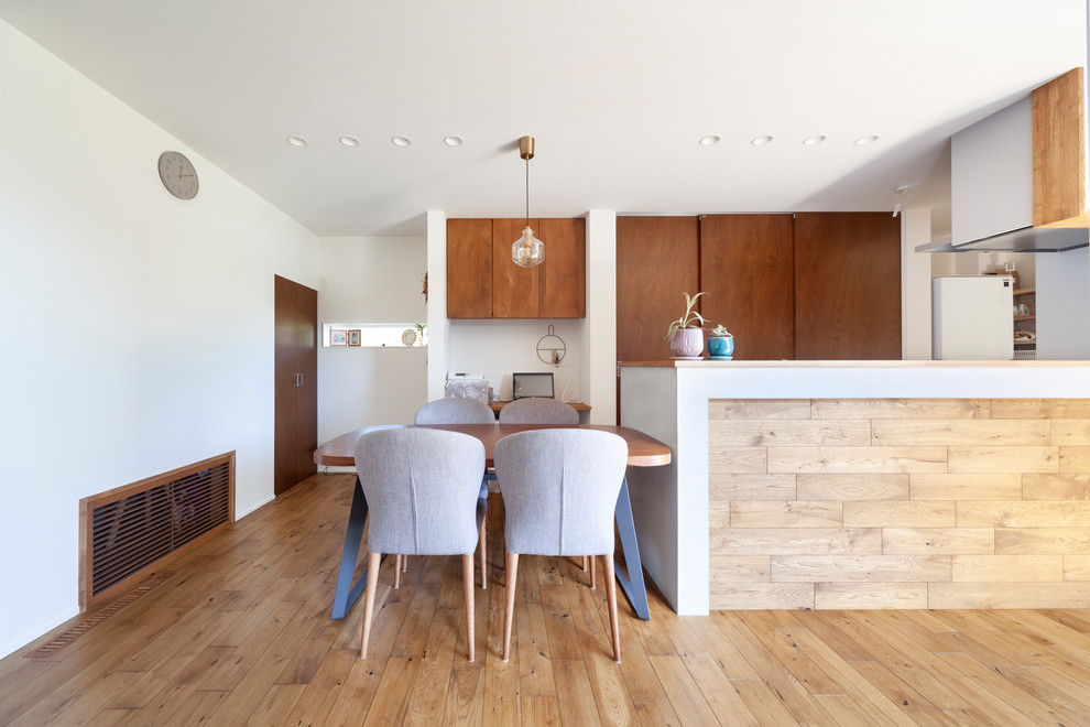 Ispirazione per una sala da pranzo aperta verso il soggiorno scandinava di medie dimensioni con pareti bianche, pavimento marrone e pavimento in legno massello medio