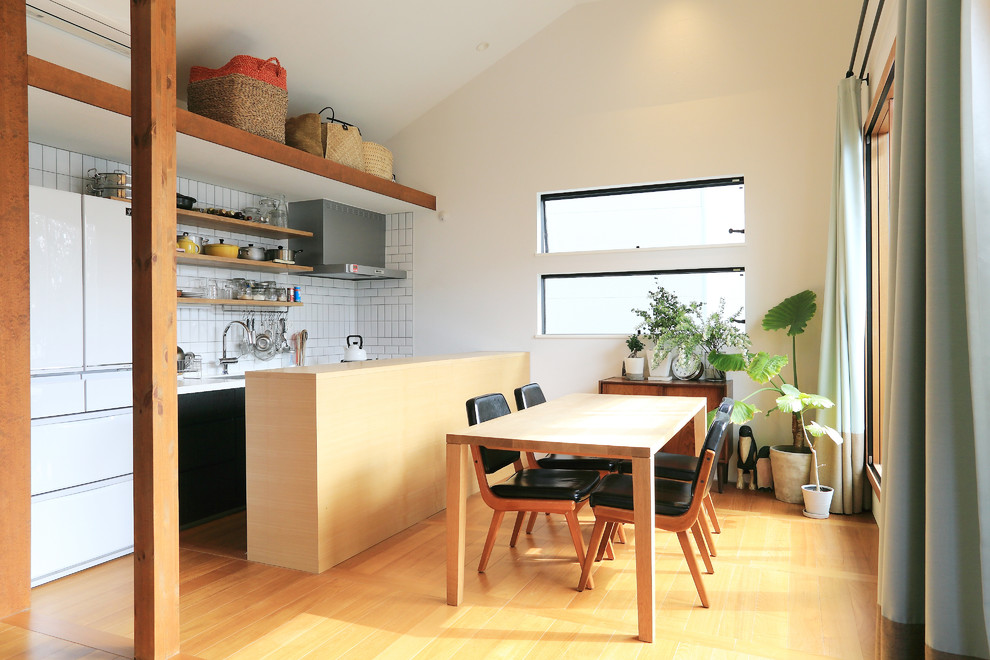 Asiatisk inredning av ett litet kök med matplats, med vita väggar, plywoodgolv och brunt golv