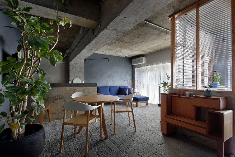 Foto di una sala da pranzo aperta verso il soggiorno industriale con pareti grigie e pavimento grigio