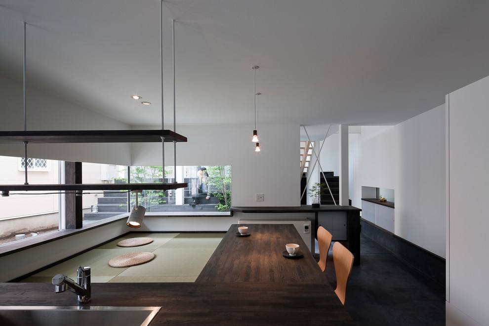 Immagine di una sala da pranzo aperta verso il soggiorno etnica con pareti bianche, pavimento nero e pavimento in tatami