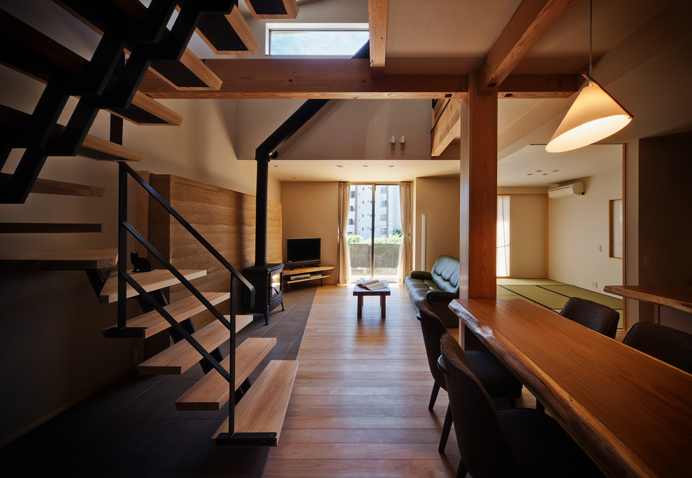 Offenes Asiatisches Esszimmer mit weißer Wandfarbe, braunem Holzboden, Kaminofen, Kaminumrandung aus Stein und braunem Boden in Kobe