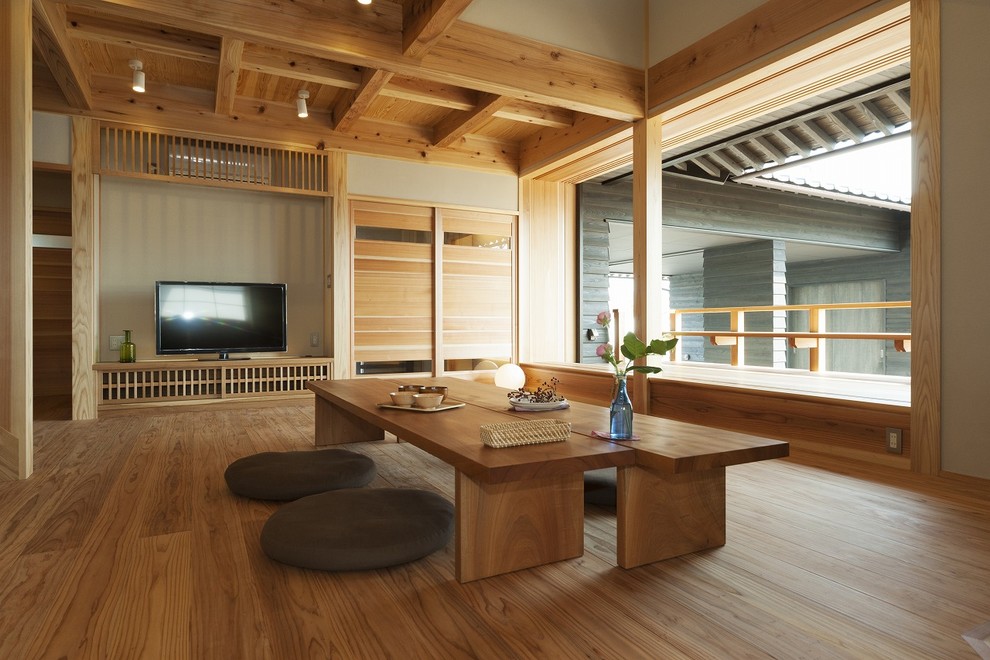 Cette photo montre une salle à manger ouverte sur le salon asiatique avec un sol en bois brun et un mur beige.