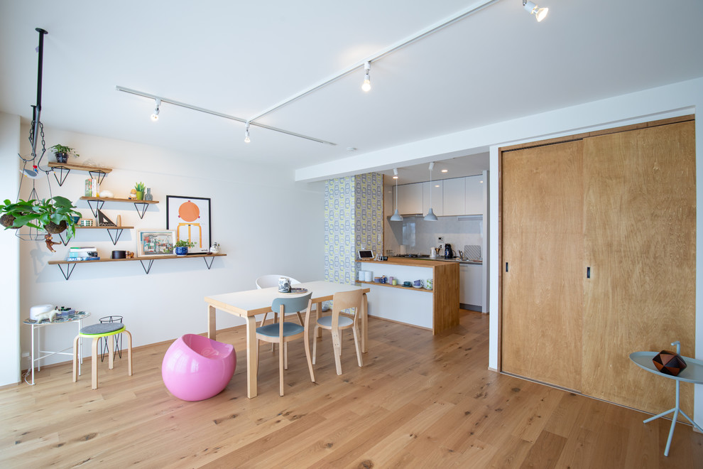 Bild på en liten minimalistisk matplats med öppen planlösning, med vita väggar, mellanmörkt trägolv och brunt golv