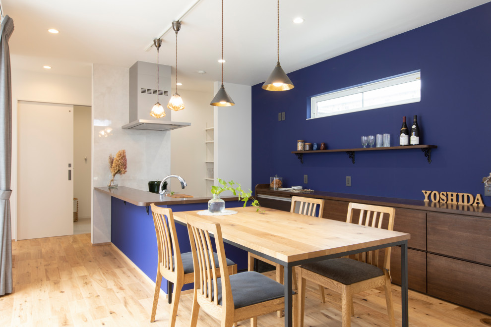 Inspiration pour une salle à manger ouverte sur la cuisine minimaliste avec un mur bleu et un sol en bois brun.