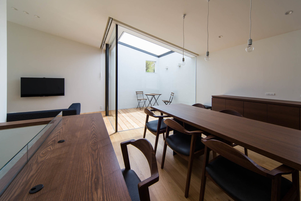 Idée de décoration pour une salle à manger minimaliste avec un mur blanc, parquet clair et un sol marron.