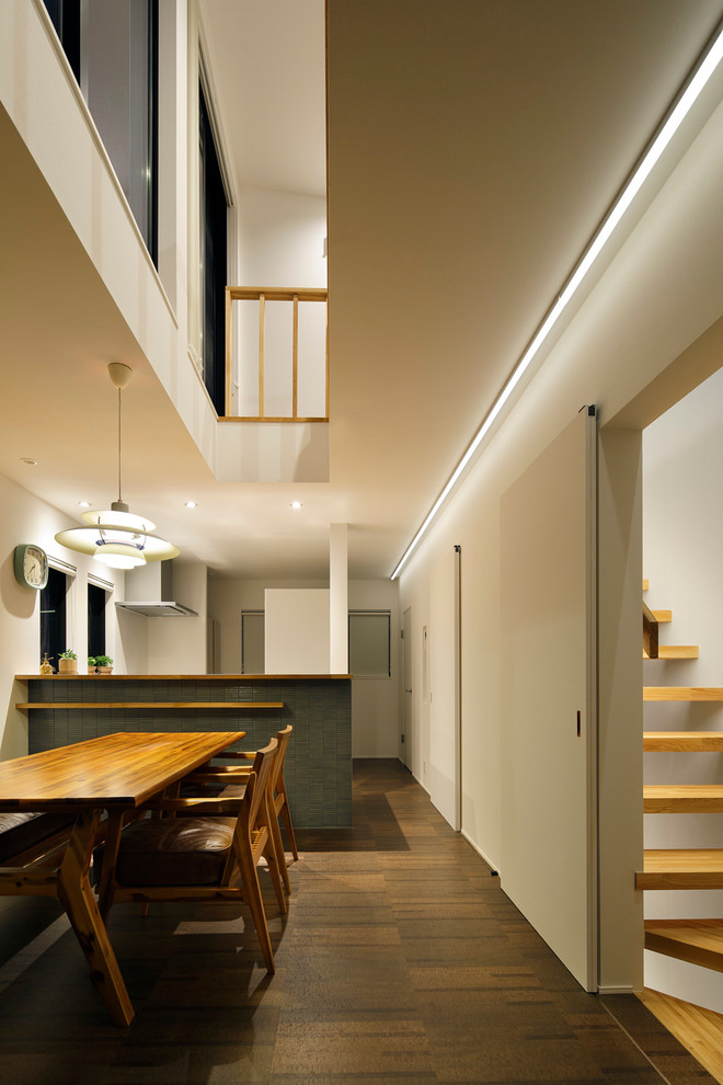 На фото: кухня-столовая среднего размера в стиле модернизм с белыми стенами и темным паркетным полом без камина с