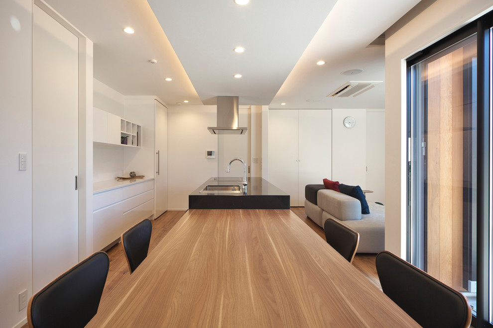 Diseño de comedor moderno abierto con paredes blancas, suelo de madera en tonos medios y suelo marrón