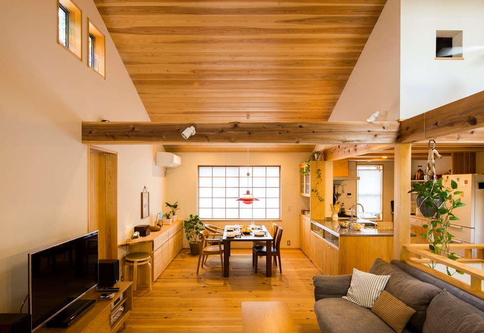 Exemple d'une salle à manger ouverte sur le salon asiatique avec un mur blanc, un sol en bois brun et un sol marron.