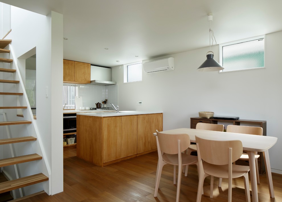 Foto di una piccola sala da pranzo aperta verso la cucina moderna con pareti bianche e pavimento in legno massello medio