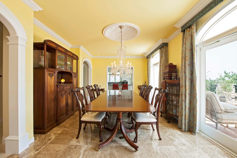 Idee per una sala da pranzo mediterranea chiusa con pareti gialle, pavimento in marmo e pavimento marrone