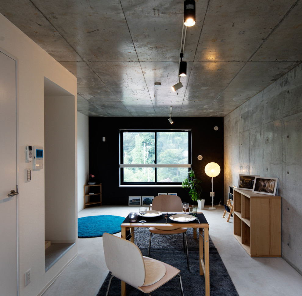 Cette image montre une salle à manger ouverte sur le salon minimaliste avec un mur gris, sol en béton ciré et un sol gris.