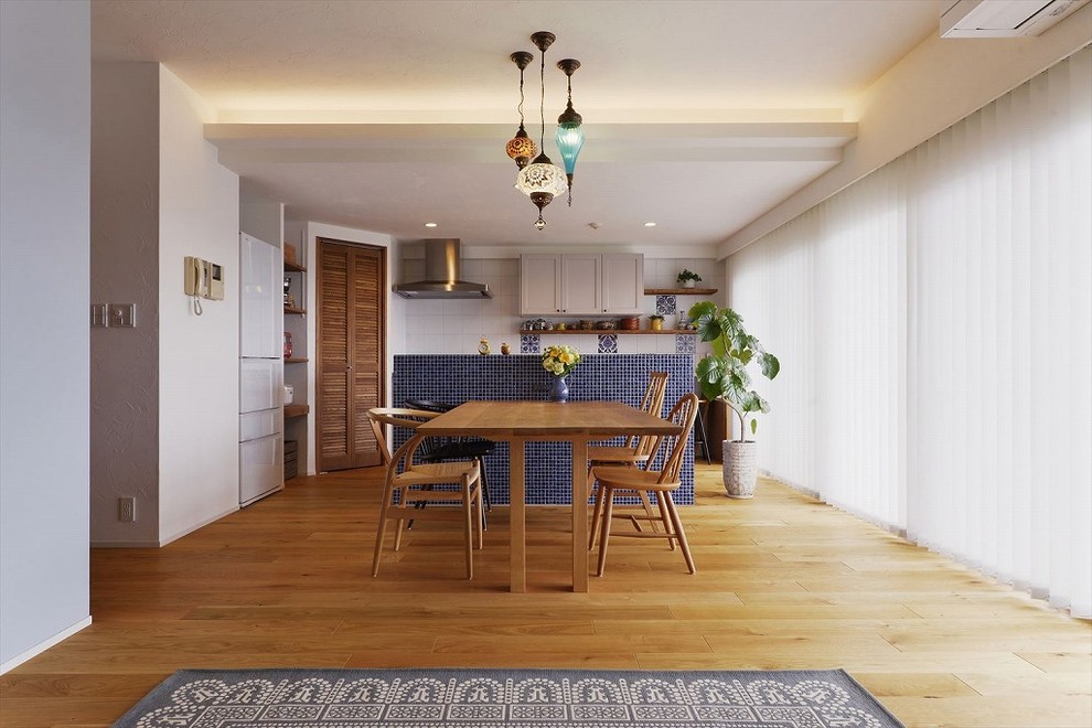 Réalisation d'une salle à manger ouverte sur le salon méditerranéenne avec un mur blanc, un sol en bois brun et un sol marron.