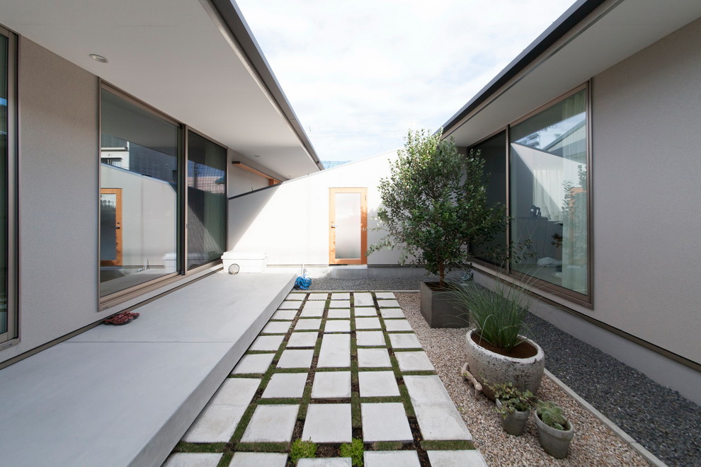 Aménagement d'une terrasse moderne avec une cour, des pavés en pierre naturelle et une extension de toiture.