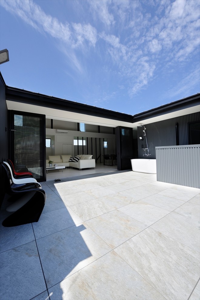 Ispirazione per un ampio patio o portico minimalista davanti casa con piastrelle