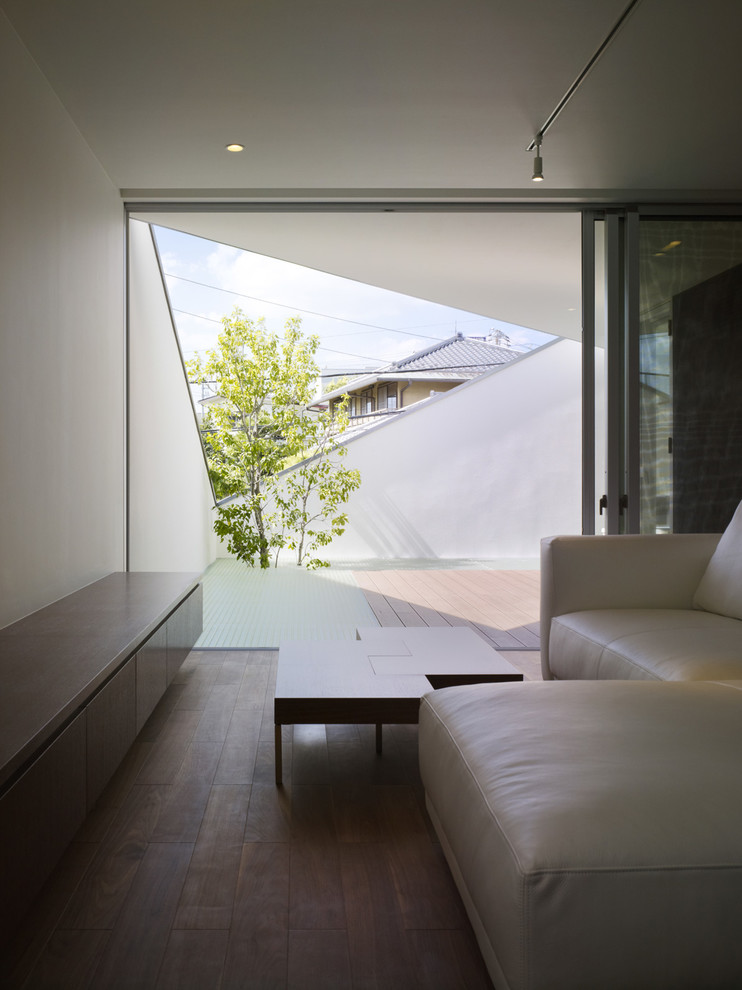 Cette image montre un salon minimaliste de taille moyenne et ouvert avec un mur blanc, un sol en contreplaqué, un téléviseur indépendant et un sol marron.