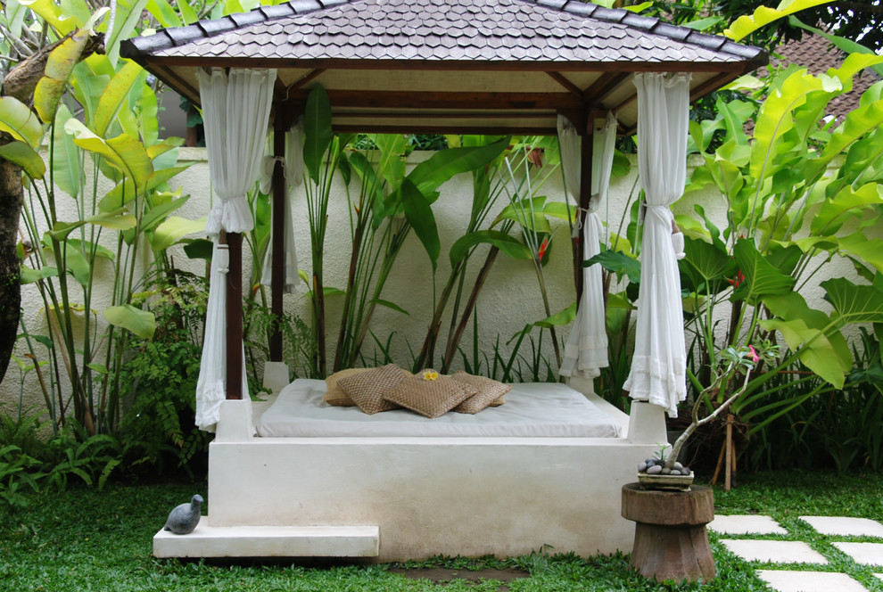 Esempio di un patio o portico tropicale con un gazebo o capanno