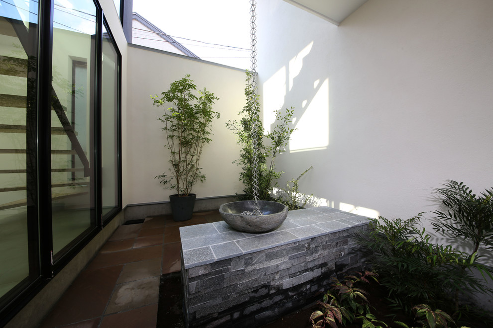 Diseño de patio minimalista de tamaño medio en patio con jardín de macetas y suelo de baldosas