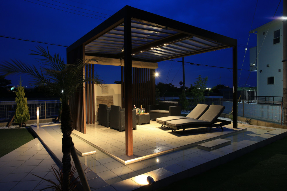 Idee per un grande patio o portico tropicale nel cortile laterale con piastrelle e un parasole