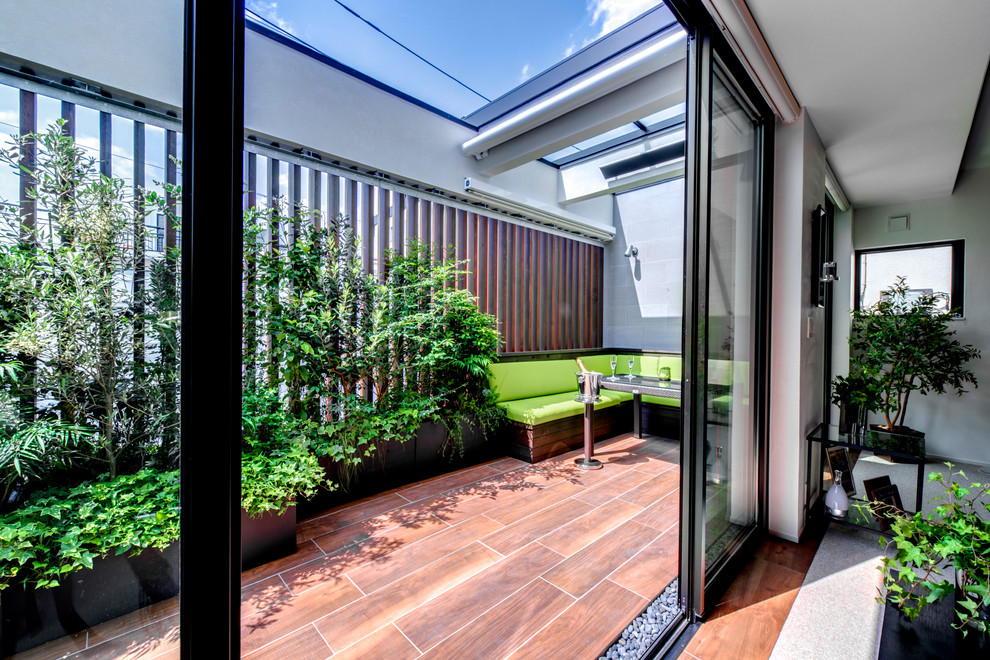 Modelo de patio minimalista de tamaño medio en anexo de casas y patio con cocina exterior y entablado