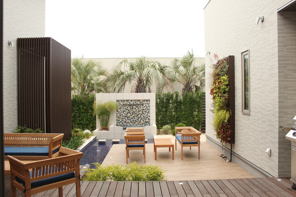 Esempio di un patio o portico tropicale in cortile con pedane e nessuna copertura