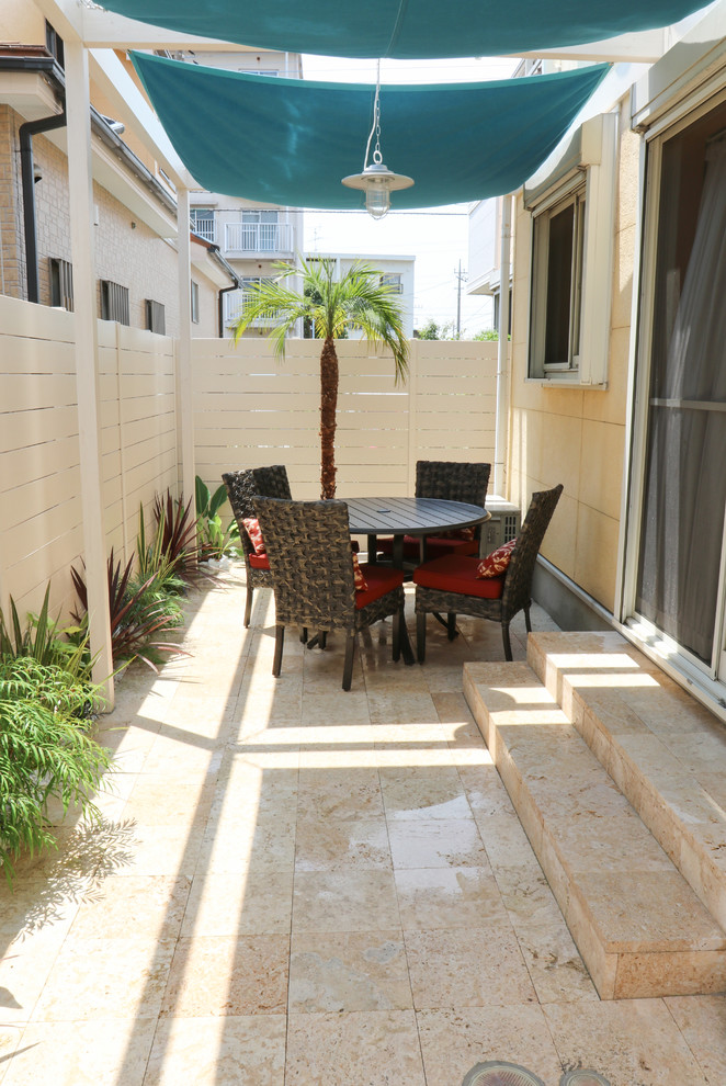 Idée de décoration pour une terrasse latérale marine avec une cuisine d'été, des pavés en pierre naturelle et un auvent.