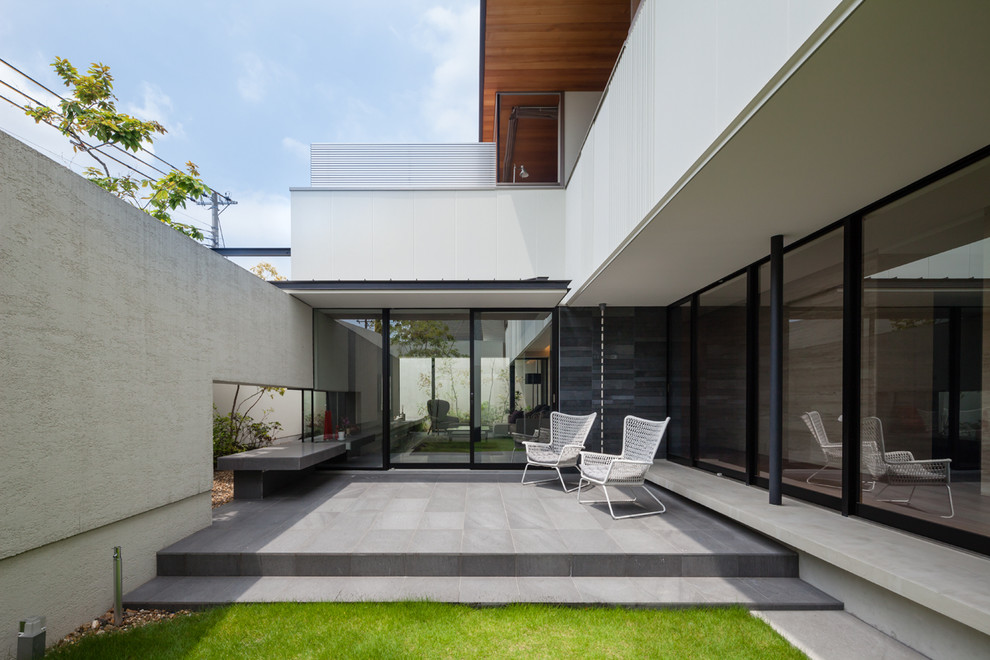 Unbedeckter Moderner Patio neben dem Haus mit Natursteinplatten in Kobe