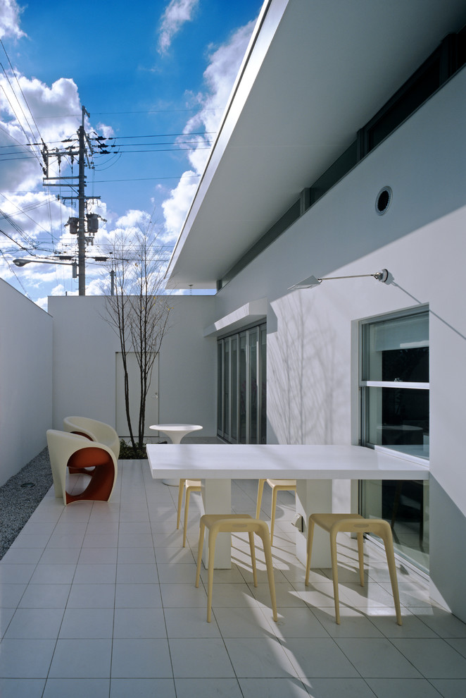 Idee per un patio o portico etnico di medie dimensioni con piastrelle e un tetto a sbalzo