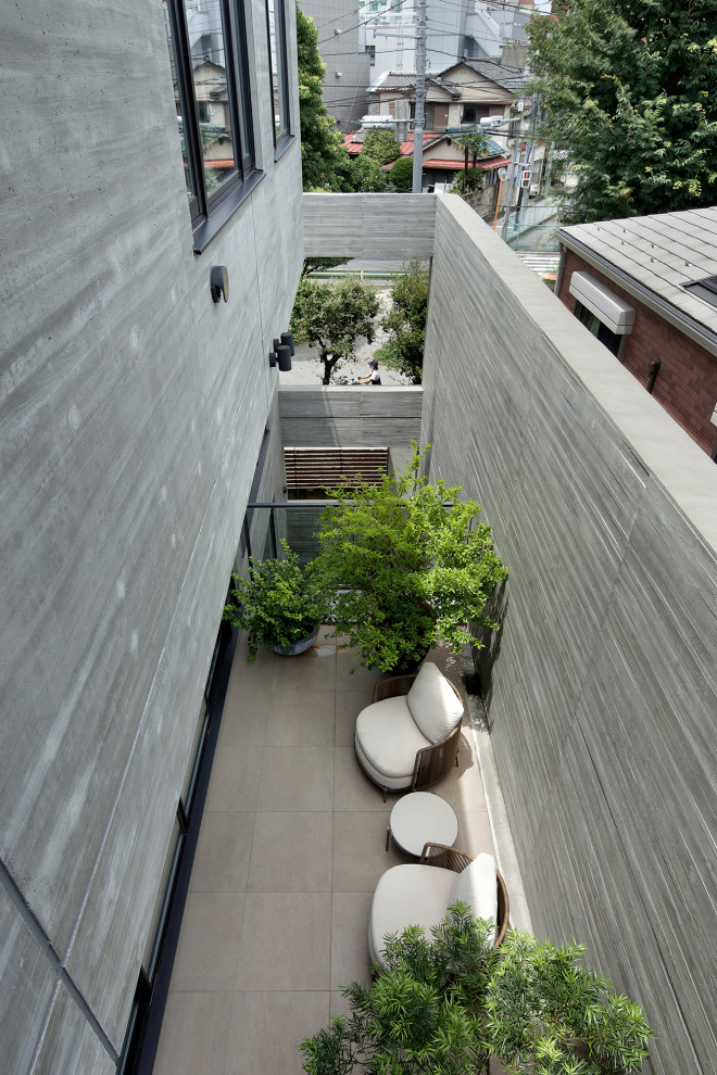 Idée de décoration pour une grande terrasse latérale minimaliste avec du carrelage et une extension de toiture.