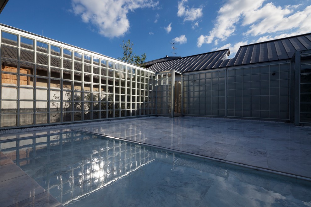 Cette image montre une terrasse minimaliste avec un point d'eau, une cour, du carrelage et aucune couverture.